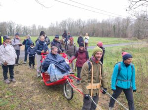 photo couleur d'une randonnée solidaire en Périgord, montrant un handicapé ou PMR dans une Escargoline tractée par des bénévoles (mules et pilote) de l'association ÇA ROULE POUR TOI sur un sentier forestier de Dordogne